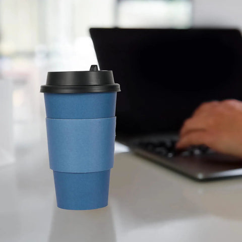 Blue 16 oz disposable paper coffee cup with lid and sleeve on desk, part of 100 pack for cafes, offices, hot and cold drinks.
