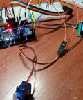 Blue SG90 micro servo connected to a development board with colorful wires; small blue LCD module on the right.