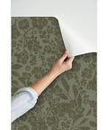 Hand peeling back Cozy Cottage Botanical Peel And Stick Wallpaper Removable Linen Texture for easy application.