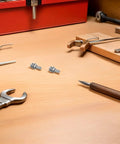 Solid 108 Piece Stainless Steel Screw Kit With Matching Nuts And Washers on a workshop table with tools.