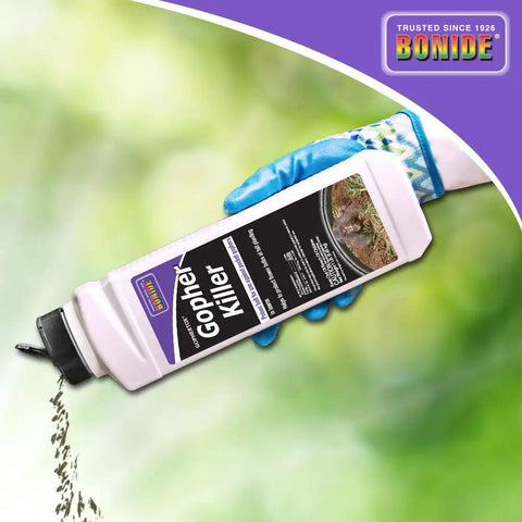 Person holding Gophertox Gopher Killer Poison Bait Granules bottle with green background, product pouring from the spout