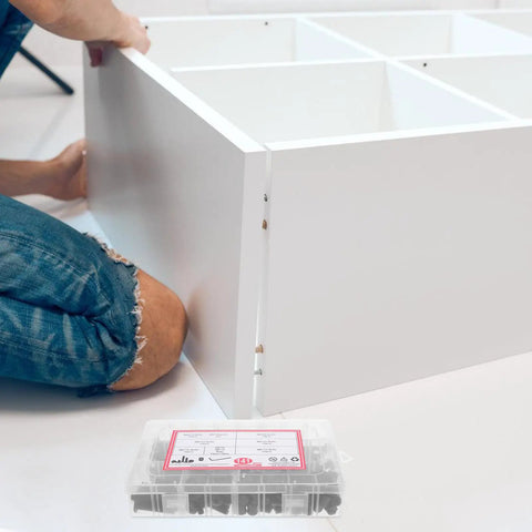 Person assembling white furniture with 141 Piece Replacement Screws Kit With Aluminum Alloy Bolts And Nuts for DIY repairs nearby