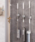 Heavy Duty Wall Mount Broom And Mop Holder Organizer For Home Garage Laundry with three tools on gray wall
