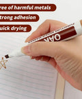 Hand using an oak wood repair marker for quick dry, non-toxic ink application on paper for DIY projects.