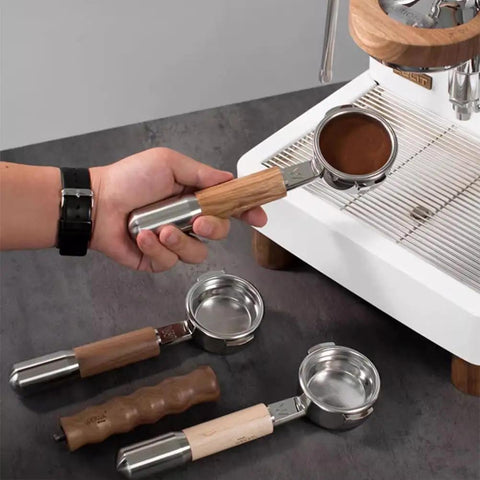 Person holding Bottomless 58mm Portafilter For E61 Grouphead Espresso Machines Pro Grade Naked Portafilter With Stainless Steel Body And Zebra Wood Handle Includes Filter Basket near espresso machine.