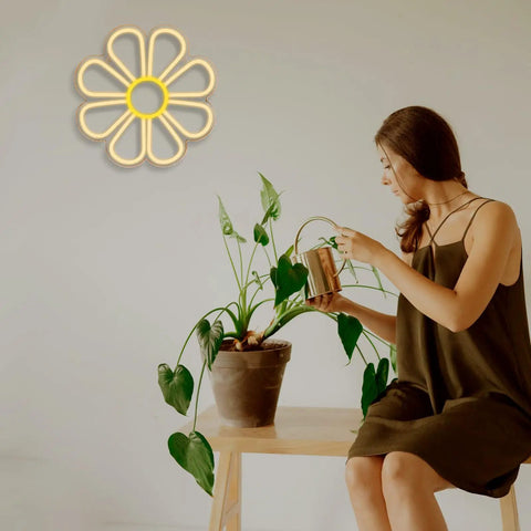 Flower Neon Sign Daisy Window Light LED Warm White For Bedroom Decor on wall, woman watering plant nearby
