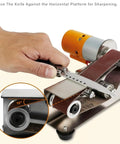 Mini Electric Belt Sander Boasts Seven Variable Speed Settings And Ergonomic Handles For Steady Precision Grinding Or Metal Polishing Hella Dependable Diy Power Tool Ships With Ten Graded Sanding Belts Ready For Fast Furniture Restorations And Quick Shop, with knife positioned on horizontal platform for sharpening.