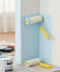 Premium Paint Roller Featuring Dual Yellow Strip Guide For Consistent Latex Flow Zero Streaks Killer Coverage Easy Peasy Application on blue wall.