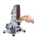 Heavy Duty 110 V Mini Bench Belt Sander Grinder For Polishing Sharpening Edge Trimming Industrial Stainless Steel Build in use with hand holding gold piece.