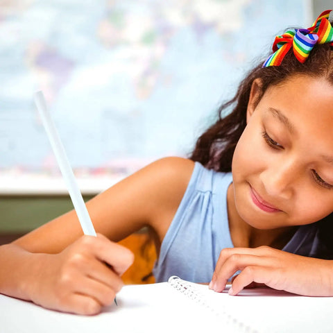 Child writing with Rainbow Paper Pencils Set 24 Pieces Number 2 HB Graphite Pencils With White Barrels in a classroom.