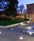 12 Pack 1W COB LED Low Voltage Landscape Ground Lights With Wire Connectors illuminating a pathway at dusk in a garden setting
