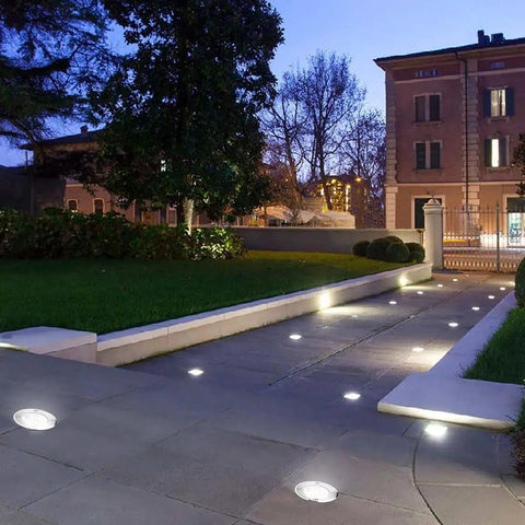 12 Pack 1W COB LED Low Voltage Landscape Ground Lights With Wire Connectors illuminating a pathway at dusk in a garden setting