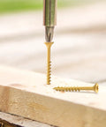 Top Shelf Rock Solid Deck Screws Ten Gauge By Three And A Half Inch Wood Fasteners Tan Epoxy Coated for maximum rust resistance being drilled into wood.