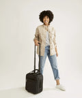 Person holding an underseat rolling work bag with laptop sleeve and botanical paisley print for commuters, softside travel ready tote.