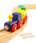 Colorful wooden toy train on tracks with two miniature wooden T nails for crafts and woodworking displayed beside it.