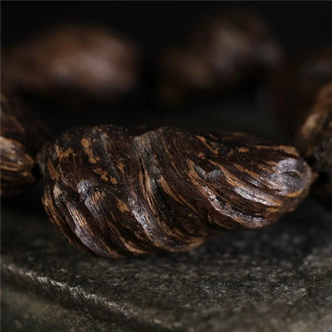 Close-up of Vietnam Nha Trang Agarwood Unisex Jewelry burl scarred black oil aged raw material with unique texture.