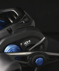 Close-up of Hagane Body Fishing Reel With Super Free Spool And Variable Braking, showing multi-color finish and control details.