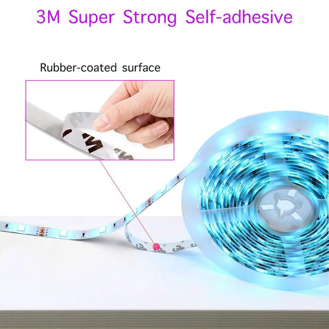 Lit 32.8 Foot RGB LED Strip Lights For Bedroom Color Changing Glow showing self-adhesive backing label close-up on roll