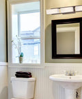 Facet 25.25 Inch 3 Light Bathroom Vanity Fixture In Tuscana Finish With White Opal Glass above a bathroom mirror and sink