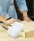 White Cushion Foam Wrap Pouches 200 Pack for packing next to person handling cardboard box on table.