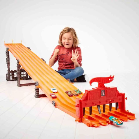 Child playing with Six Car Super 6 Lane Raceway With 8 Foot Roll Up Track, Realistic Lights And Sounds, Includes Six 1 64 Scale Vehicles.