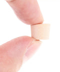 Close-up of fingers holding a single tapered wood plug for screw holes with button plug head, lightweight furniture repair cap.