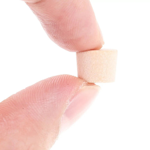 Close-up of fingers holding a single tapered wood plug for screw holes with button plug head, lightweight furniture repair cap.
