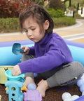 Child playing in inflatable kids pool with air pump, used as large sensory sand and water play pit. Safe, kid-friendly PVC.