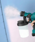 HVLP Electric Paint Sprayer Handheld With 1200ml Detachable Canister painting a blue wall, showing spray pattern.