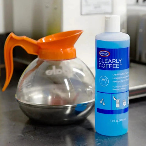 Clearly Coffee Pot Cleaner 14 Ounce Made In The USA French Press Liquid Cleaner bottle next to a glass coffee pot