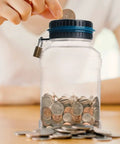 Person inserting coin into Green Digital Coin Counter Money Bank With LCD Display, 1.8L ABS Jar, lockable with two keys