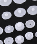Totally Awesome 64 Kinds Plastic Gears Pulley Belt Kits For Robot Motor Toys Perfect For Engineering And Model Making Projects Great Stuff For DIY Builds white plastic gears and pulleys on black background