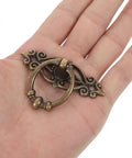 Hand holding Six Piece Vintage Bronze Bail Drawer Pulls For Dresser Cabinet Jewelry Box And Furniture Antique Round Knob Hardware Retro Vibe Durable Zinc Alloy Construction Classic Decorative Pull Handles.