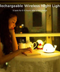 Woman reading next to Cute Whale Night Light For Kids With 7 Color Changing LEDs, Tap Control Silicone Baby Night Lamp, USB Rechargeable