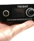 Person holding OLED T12 solder station, part of Beefed Up High Power Digital Soldering Station With 75W Quick Heat For RC Toys And FPV Builds Adjustable Temperature Auto Sleep Auto Power Off Includes T12 K Solder Tip Compatible With Common Power Adapters Power Supply Not Included.