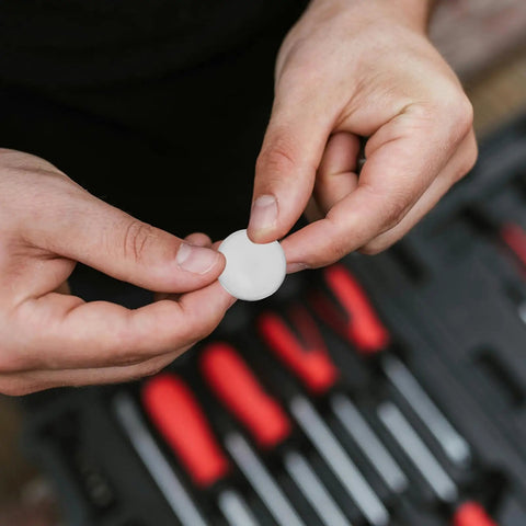 Person holding a round stainless steel knockout plug from the 10 Pack Round Stainless Steel Knockout Plugs For Junction Boxes And Electrical Panels.