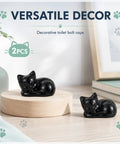 Two black cat-shaped toilet bolt caps on a wood platform for decor, part of Straight Up Adorable Cat Shaped Ceramic Toilet Bolt Covers.