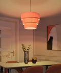 Orange Plug In Pendant Light With Three Tier Mid Century Modern Linen Shades Stylish Hanging Chandelier illuminating a dining area.