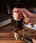 Hand pressing coffee grounds in portafilter for 4 Cup Drip Coffee Maker With Timer And Thermal Carafe Stainless Steel Coffee Brewer