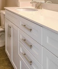 White bathroom cabinet with stainless steel T bar cabinet handles in satin brushed nickel finish installed on drawers and cupboard.