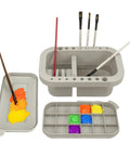 Gray Must-Have Paint Brush Cleaner And Holder With Built-In Palette And Wash Basin For Acrylic, Watercolor, And Water-Based Paints, Compact Portable Organizer displayed with brushes and paint.