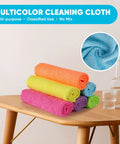 Six colorful microfiber cleaning cloths rolled on a wooden table (orange, yellow, pink, purple, blue, green).