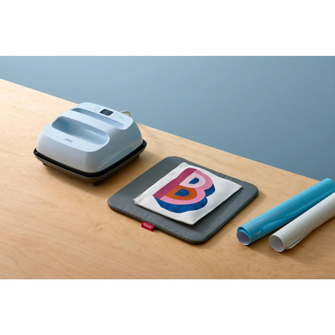 Cricut EasyPress Mat 12x12 protective heat-resistant mat, gray with red Cricut tag, beside a blue EasyPress