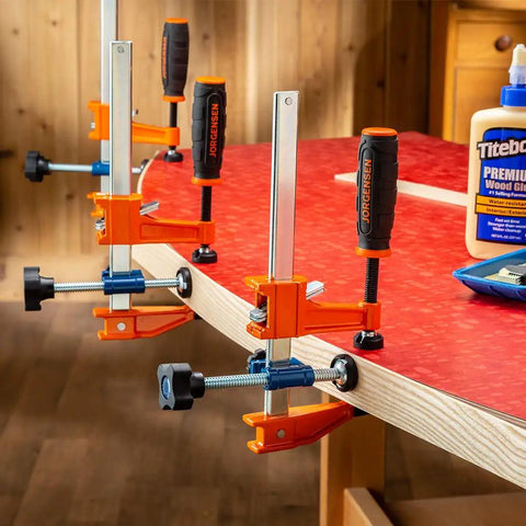 3-Way Clamp Attachment For F-Style Clamps With Single Screw Converts Your Clamp Into A 3-Way Edge And Flush Joint Tool For Welding Projects Delivers 900 PSI Using Standard Or Light Duty F Clamps Handle Clamp Tool in use on red laminated wood edge.