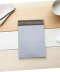 Waterproof Poly Mailer Bags 10x14 Inches White Self Seal Envelopes on a wooden table for clothing shipments