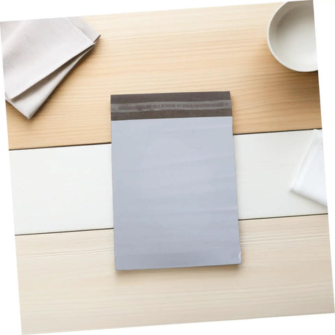 Waterproof Poly Mailer Bags 10x14 Inches White Self Seal Envelopes on a wooden table for clothing shipments