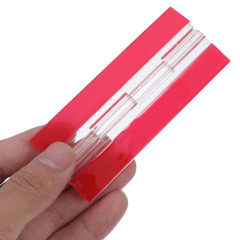 Hand holding Two Pack Acrylic Self-Adhesive Flush Cabinet Hinges 100x42mm Clear Transparent, showing red adhesive backing.