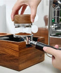 Heavy Duty Wooden Espresso Knock Box With 58mm Tamper Base, user tampering coffee grounds, showcasing dual slot design for home cafe.