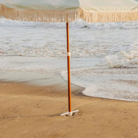 Heavy Duty Beach Umbrella Anchor With Spiral Screw Base Universal Size Fits Most Umbrellas Perfect For Sand Or Grass Keeps Your Beach Shade Steady In Windy Conditions White, shown securing umbrella in sand at the beach.