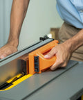 User operating No Sweat Grip Lockdown Push Block With Retractable Holder and Traction Pad on a table saw for precise control.